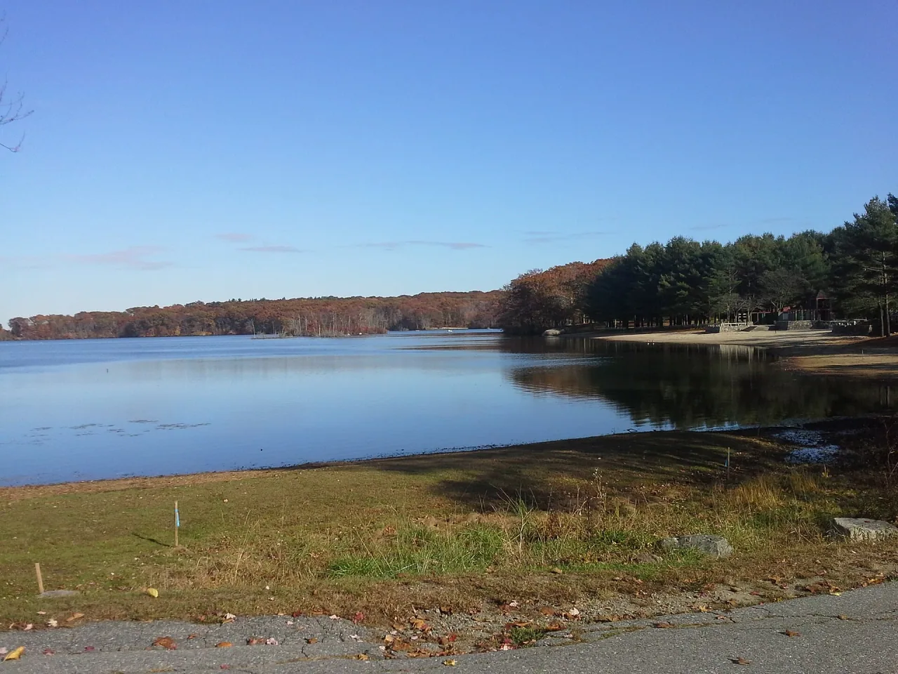 Autumn trees and the swimming beach reflect in Olney Pond at Lincoln Woods State Park.