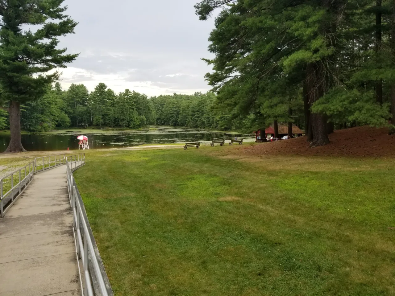 A grassy picnic area and paved path lead to the pond at Pulaski State Park.
