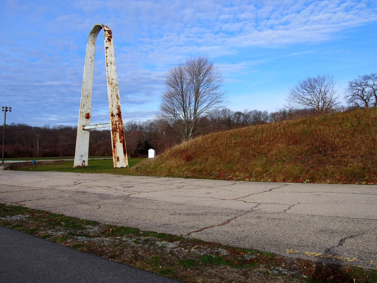The tall surviving arch at Rocky Point State Park rises beside bare trees under a blue sky.