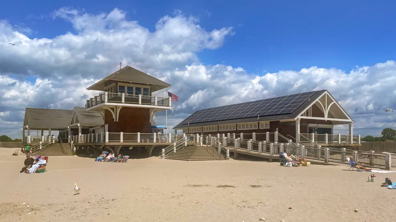 The beach pavilion at Roger W. Wheeler State Beach stands under a blue sky with white clouds.