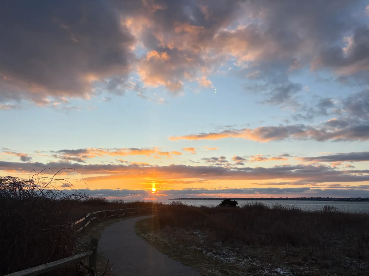 Sunset over a coastal path and water at Sachuest Point National Wildlife Refuge.